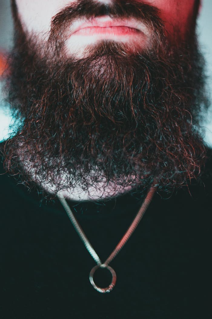 services-05 Detailed image focusing on a bearded man's chin wearing a necklace, highlighting facial hair texture.